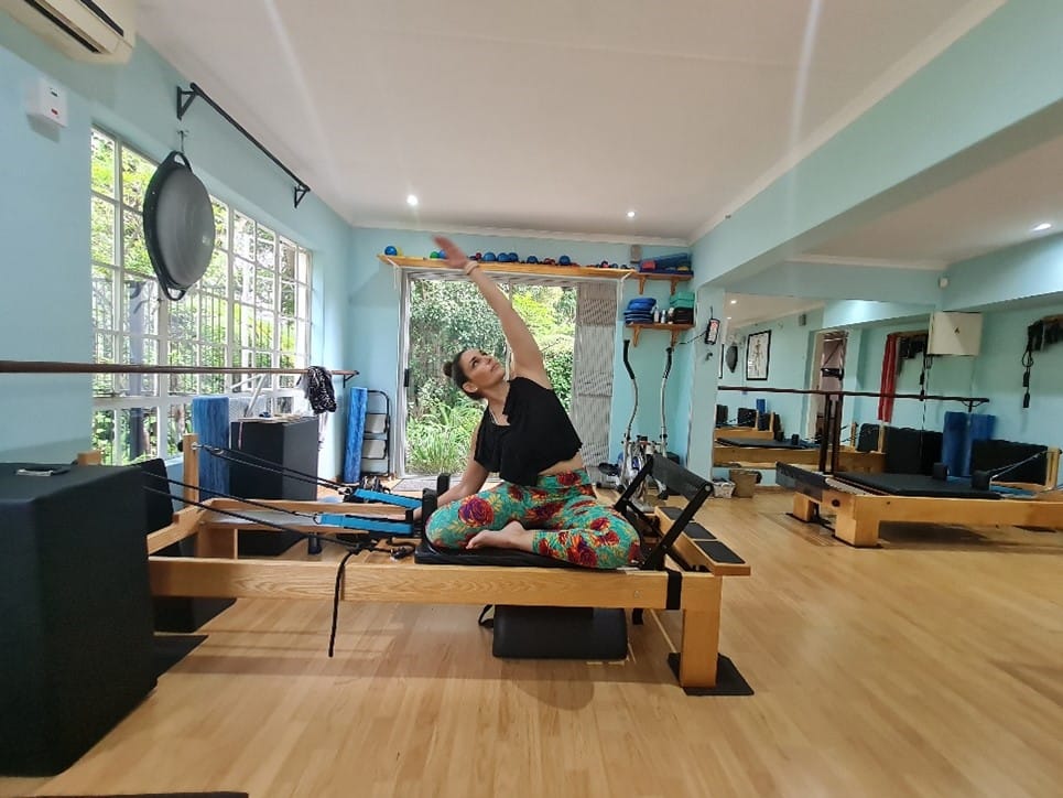 Pilates teacher demonstrating an exercise on the Reformer