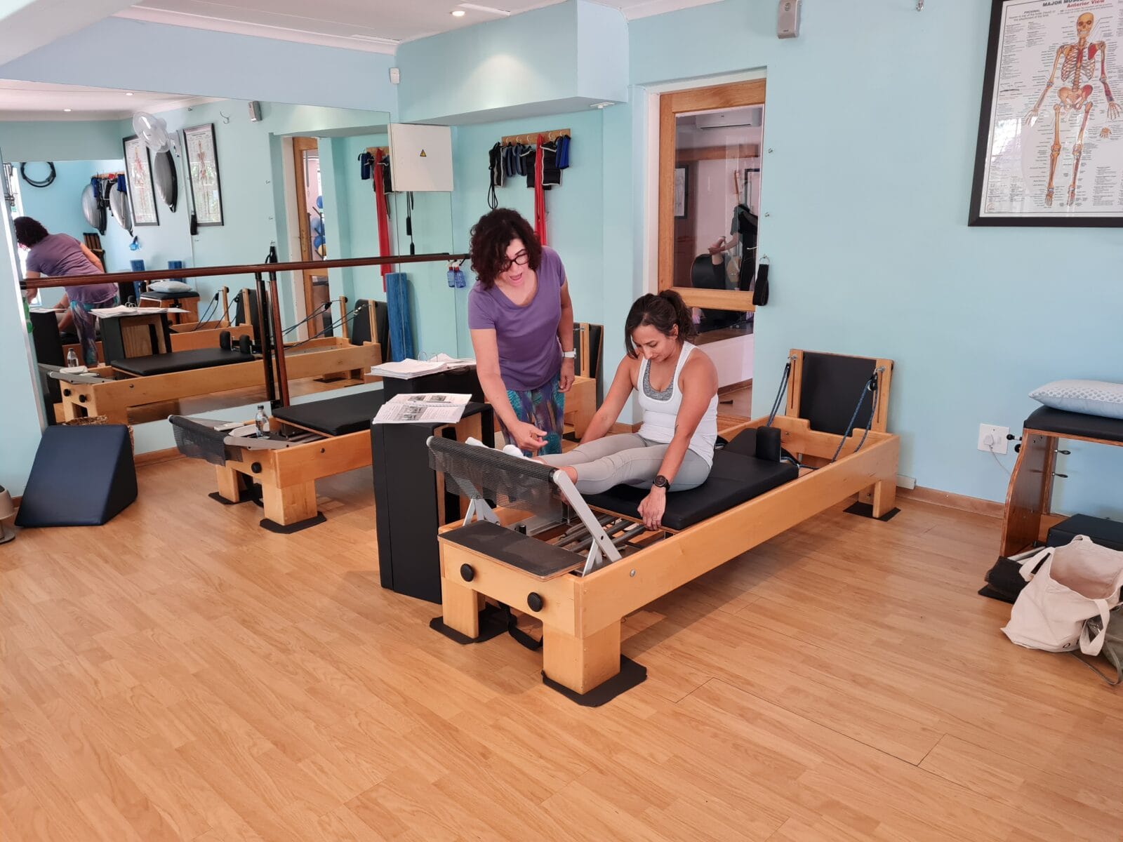 Pilates instructor guiding a client through an exercise on Pilates equipment