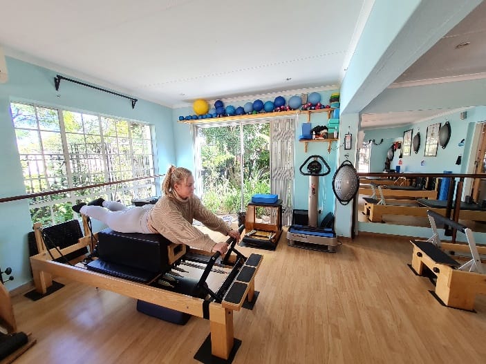 Woman performing a strengthening exercise on a Pilates workout bench