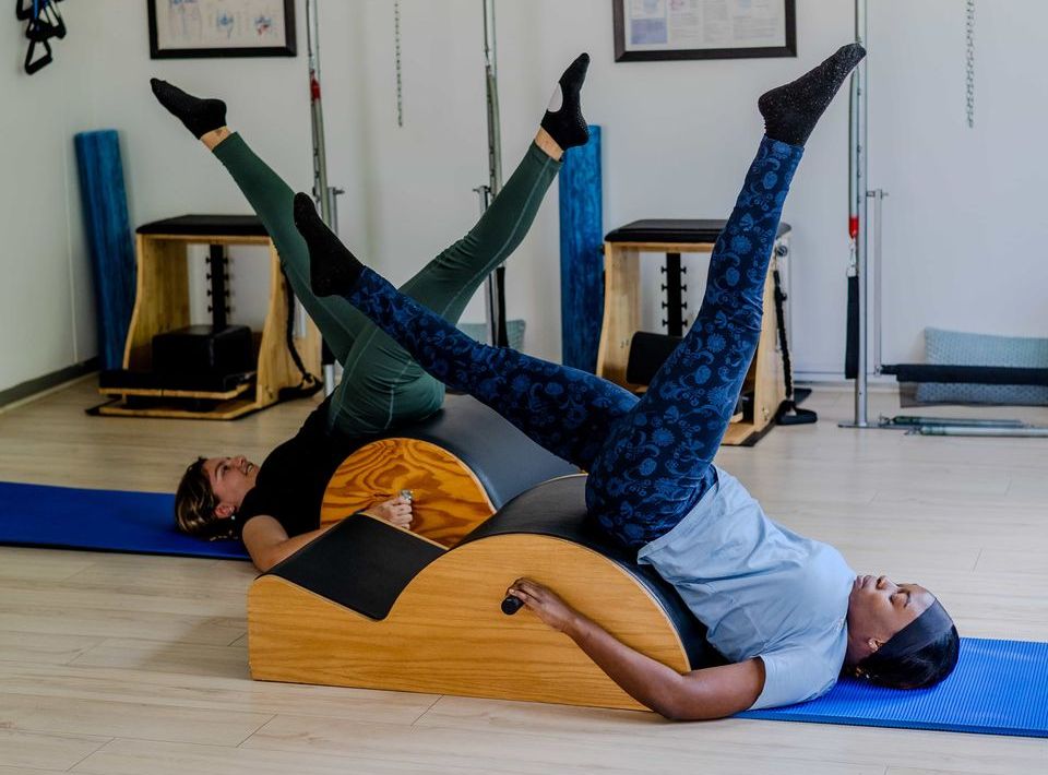 Two friends doing Pilates side by side on spine correctors at Pilates Dynamics, Randburg