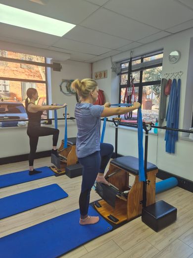 Two women standing on the chairs with their arms reaching forward