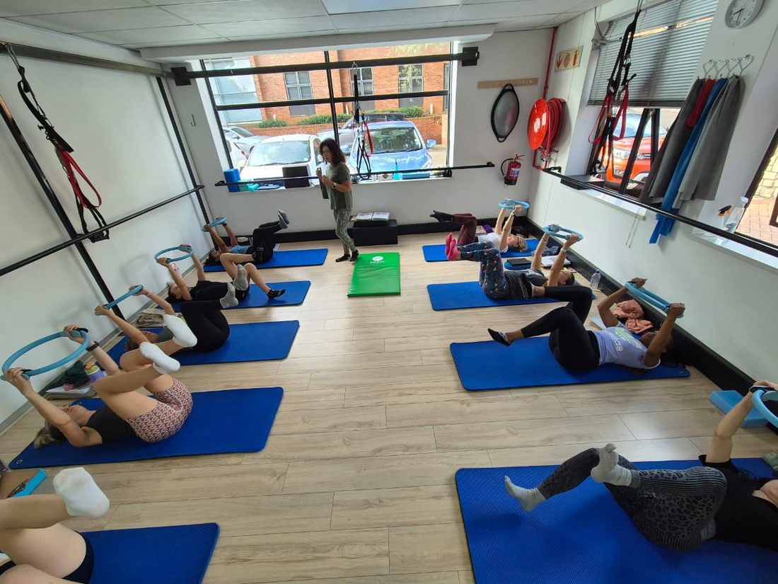 A small-group mat class working with Pilates rings